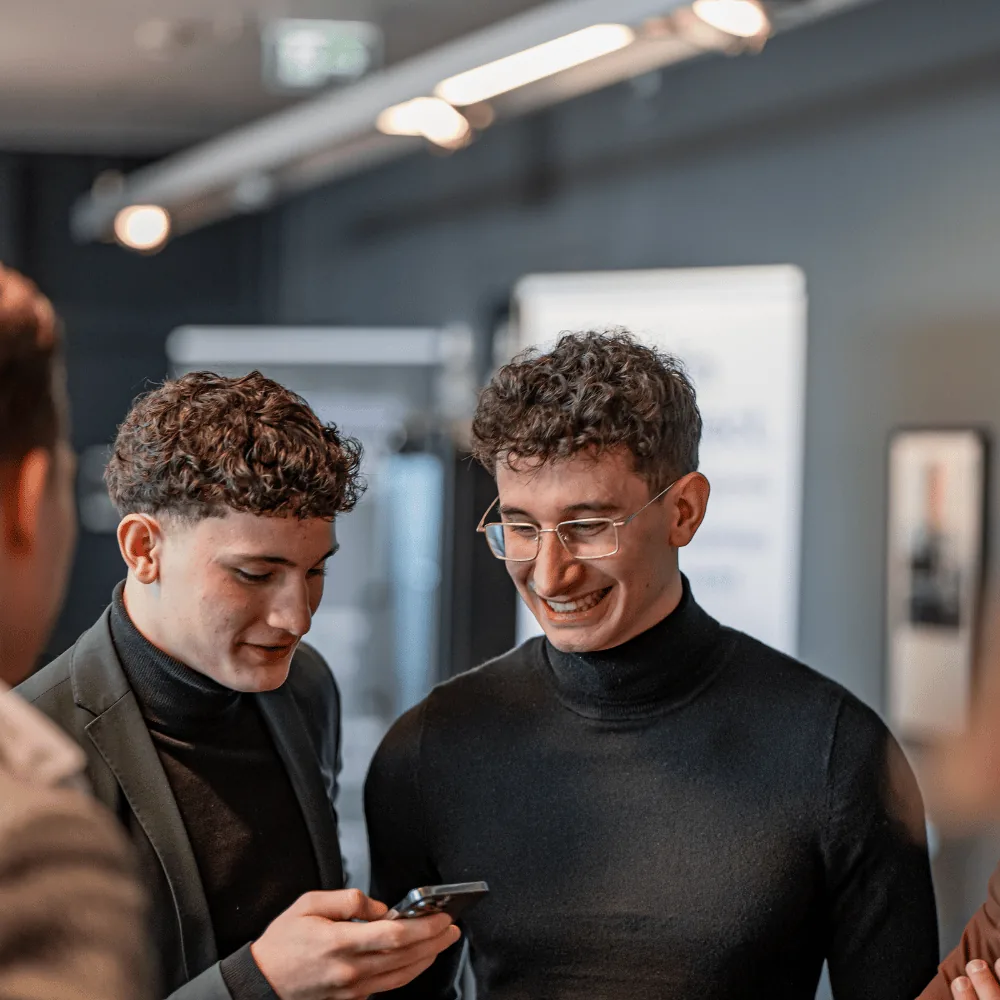 Zwei junge Berater schauen gemeinsam auf ihre Smartphones